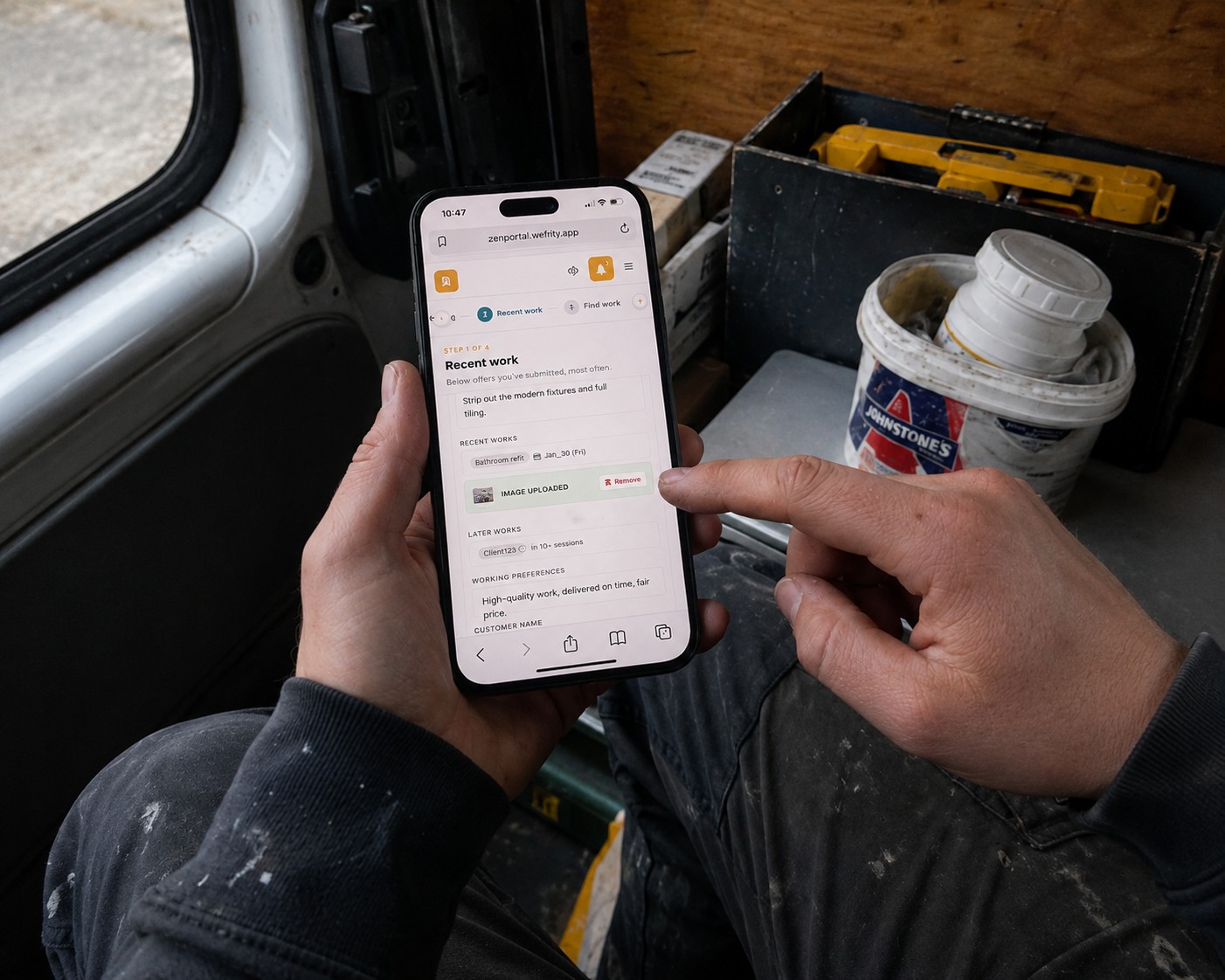 Plumber holding phone with the builder open while sitting in the van