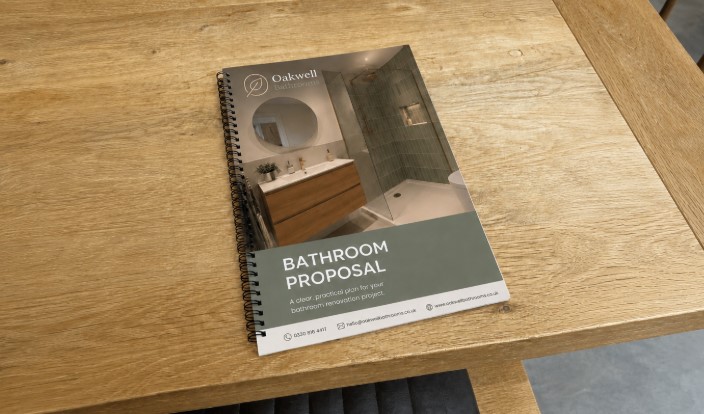 Bathroom proposal as a printed spiral-bound booklet on a wooden table